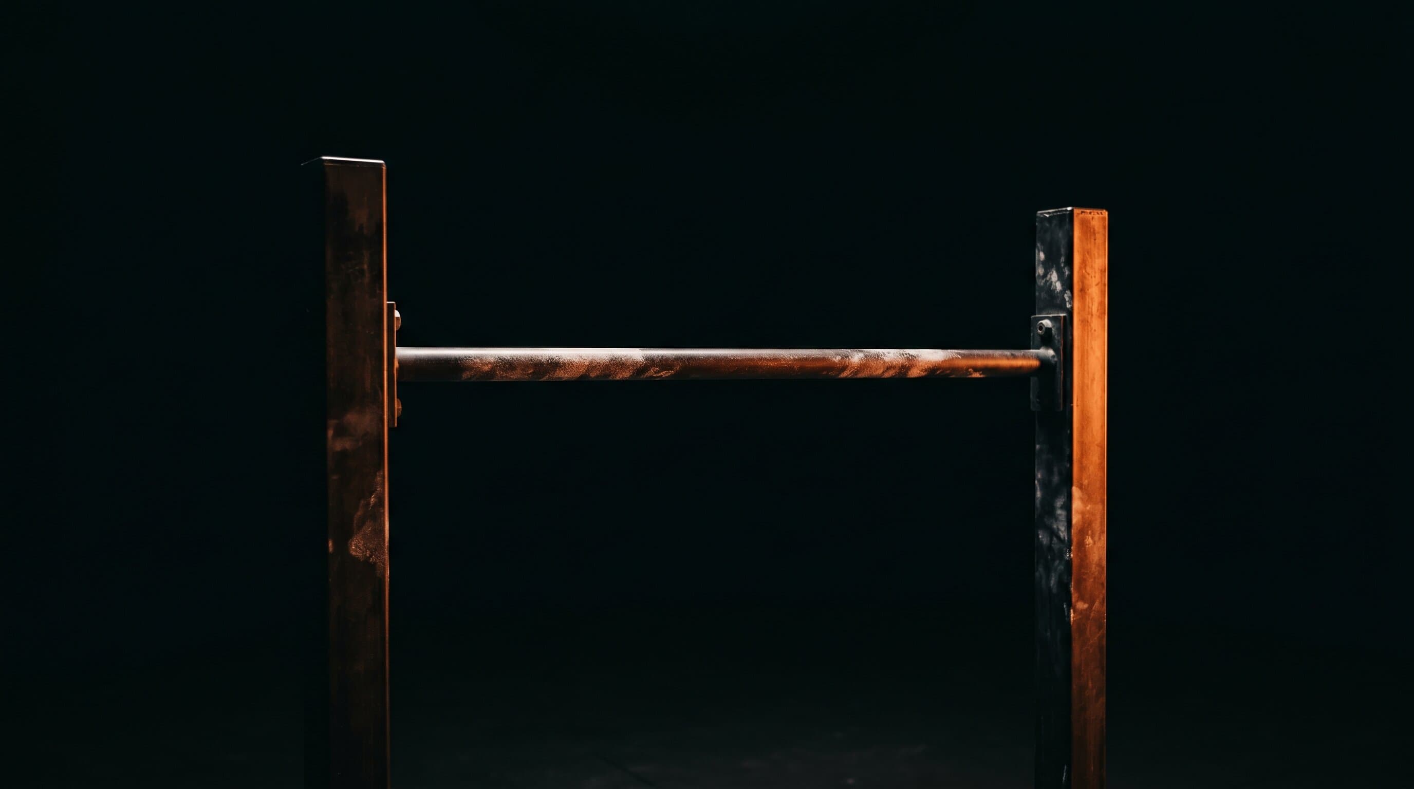 Conceptual image of a single pull-up bar lit by warm orange light against a dark background, representing an owned creator business