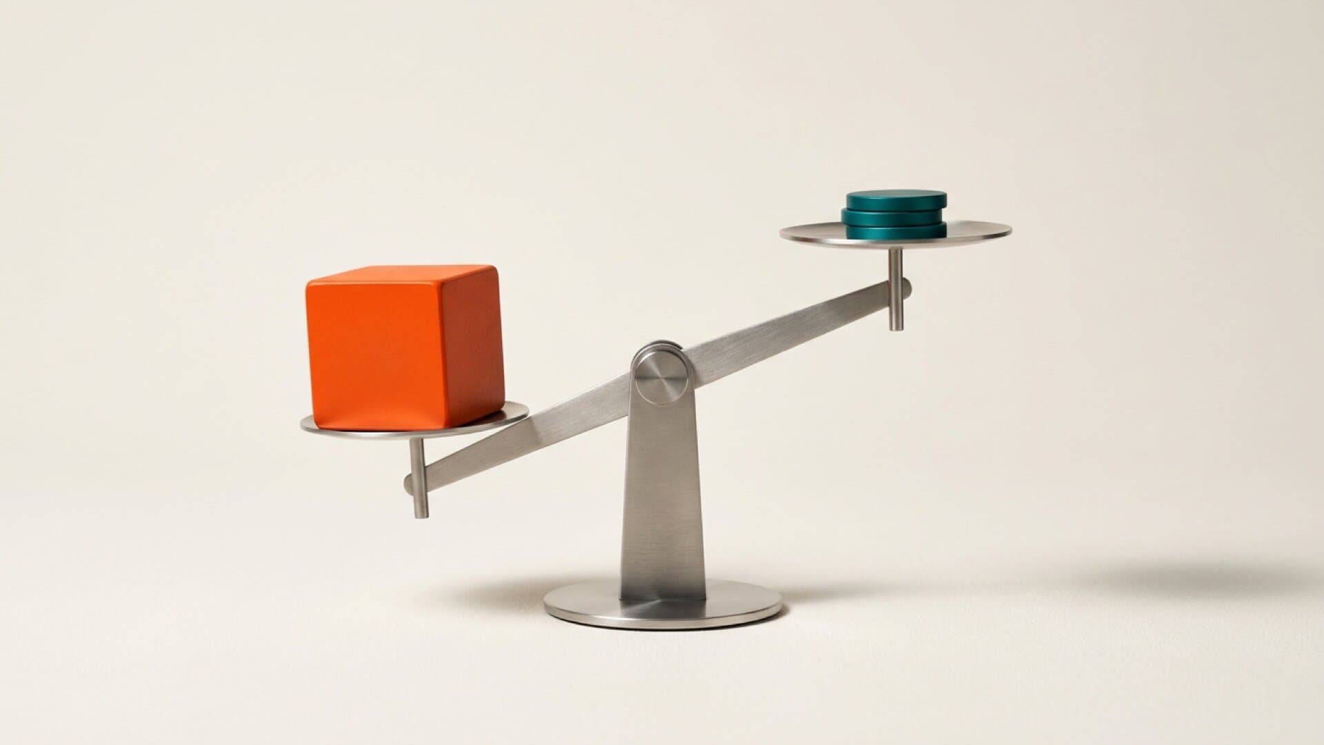 A balance scale with a large molten orange block far outweighing a small stack of teal discs, on a bright studio surface
