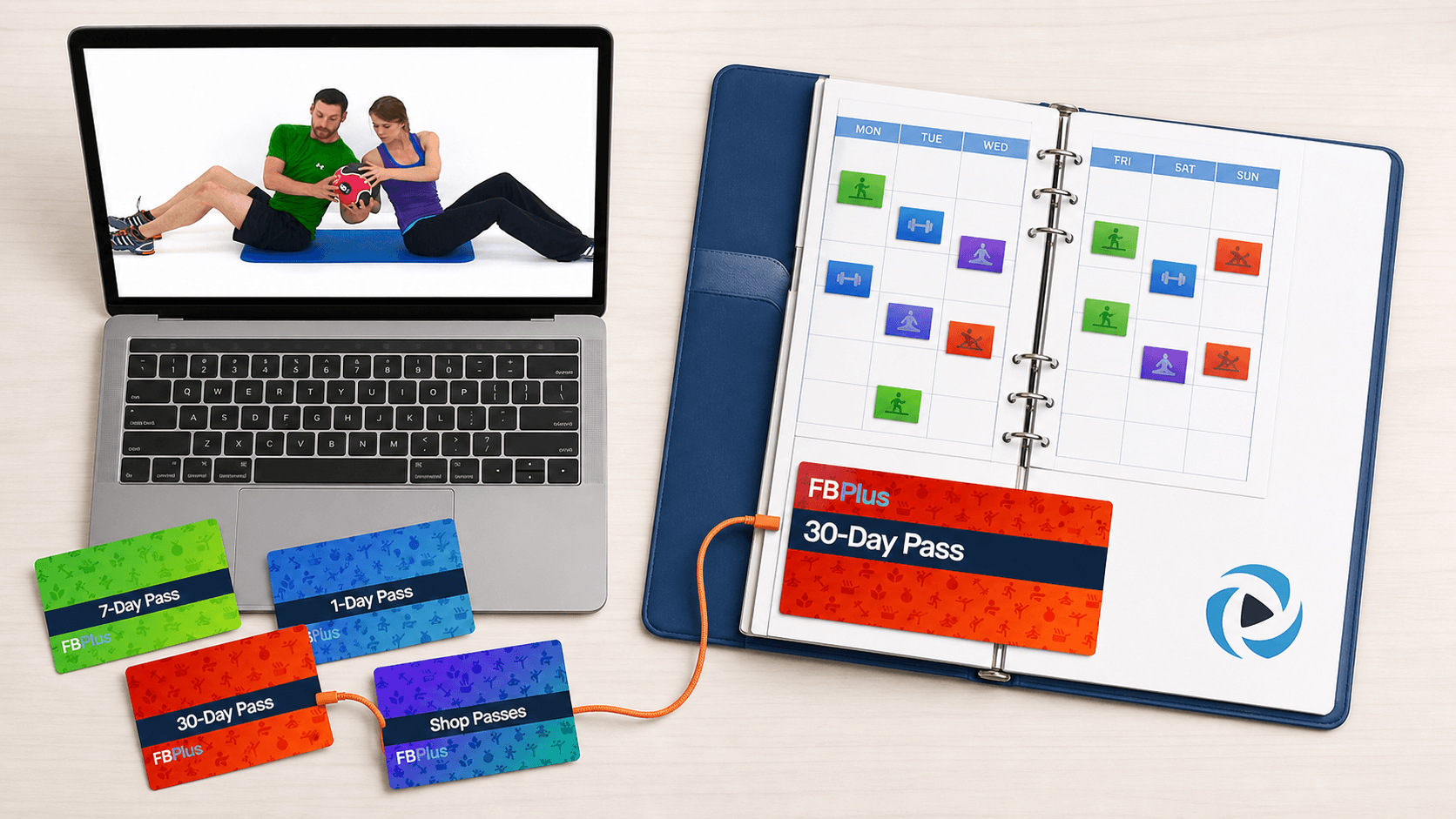 An overhead studio scene with an authentic Kelli and Daniel workout playing free on a laptop beside an FB Plus pass and organized workout calendar, showing that the workouts are free while the system is paid