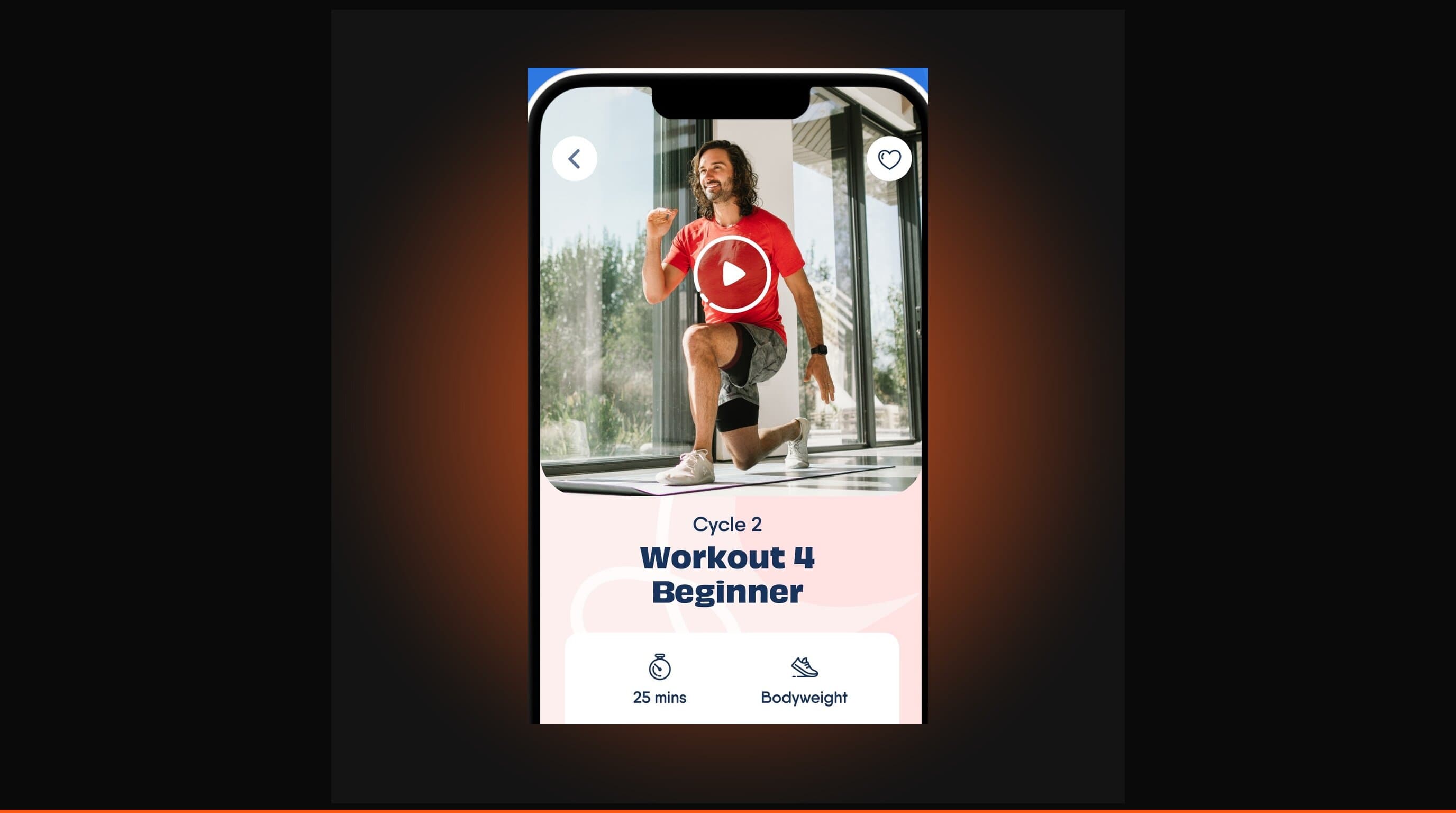 The Body Coach app shown on a smartphone beside Joe Wicks on a dark studio background with warm orange accent lighting